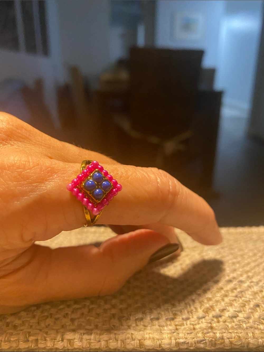 Gold, antique women’s ring with individual pink stones surrounding blue center.